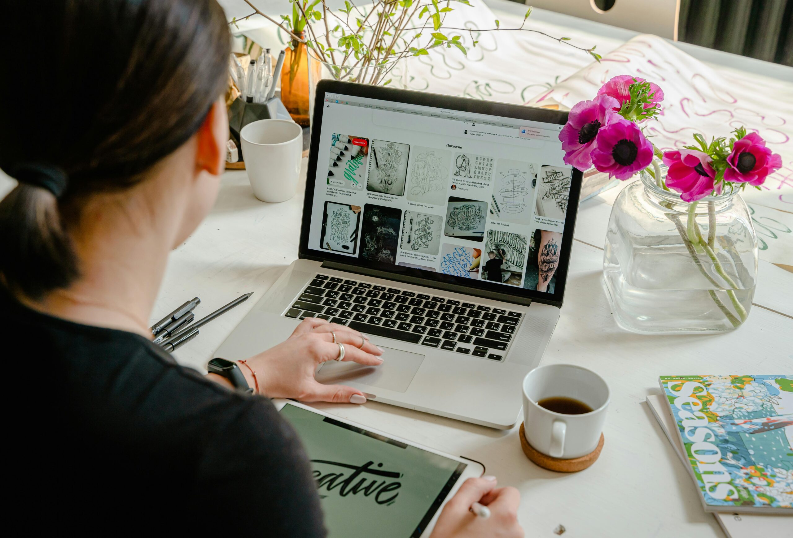 Woman in a creative workspace using a laptop and tablet for calligraphy. Artistic and tech-driven environment. We design a Professional  logo
