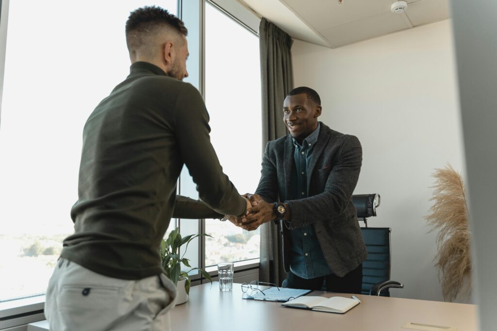 Two businessmen exchanging a handshake during a professional meeting in a modern office setting. Ultimate guide to hire a Digital Marketing Strategist in 2025