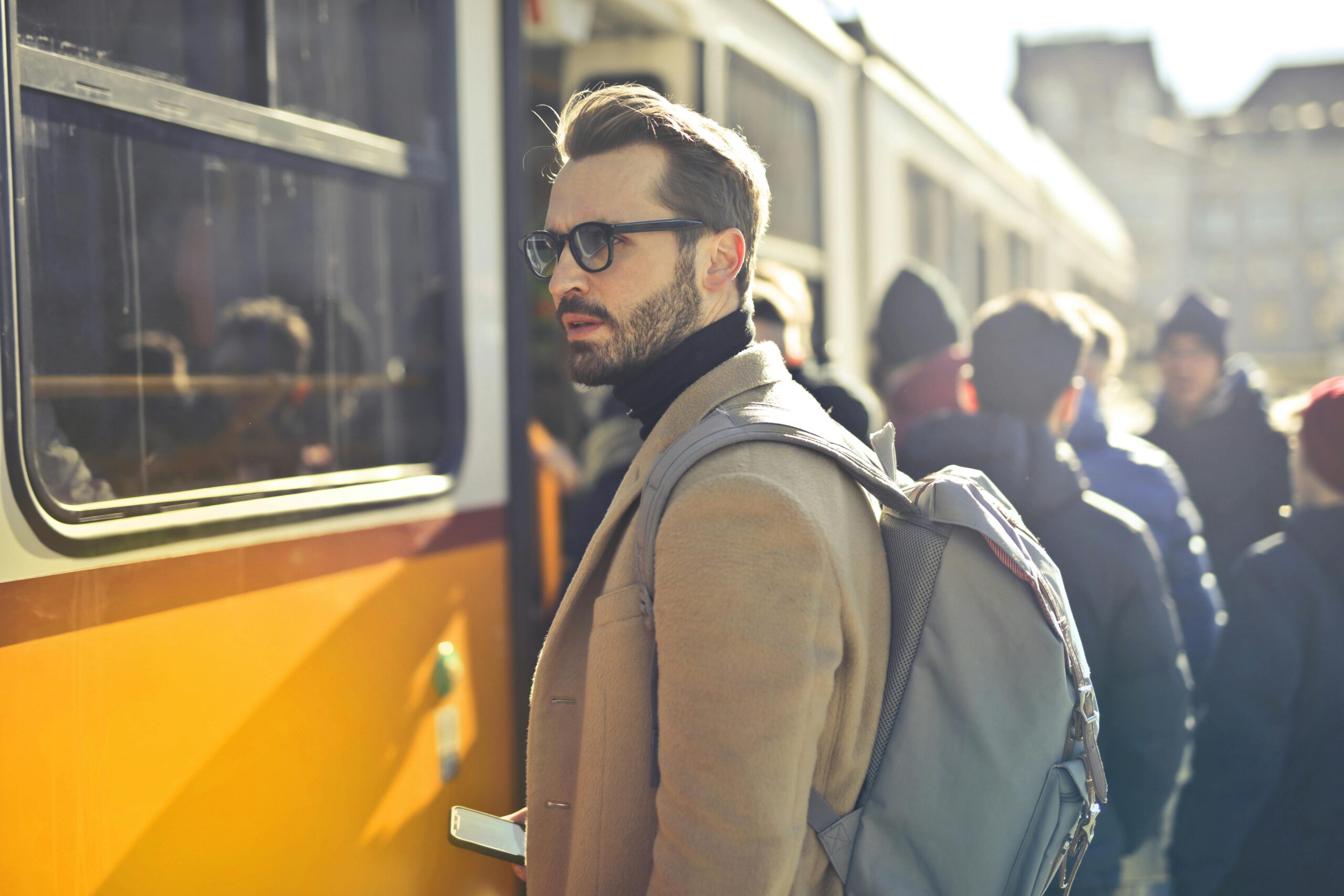 A stylish man with a backpack boards a tram in bustling Budapest, Hungary, during the day.Digital Marketing Strategist